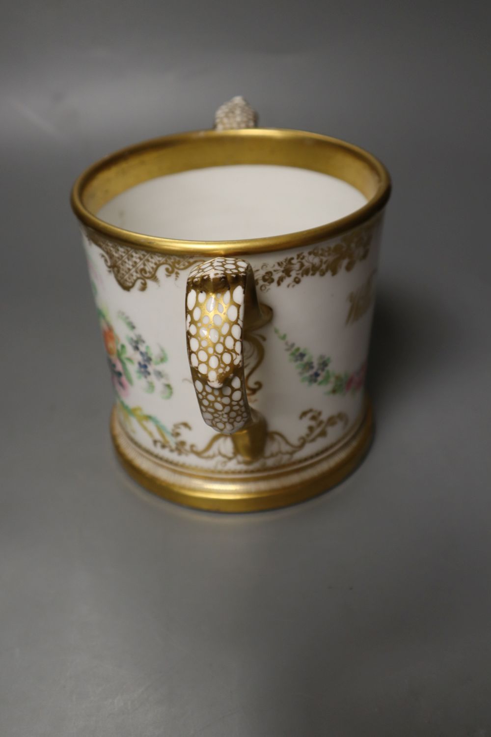 An English porcelain two handled mug lavishly painted with flowers, inscribed verso William Brown 1854, 14cm